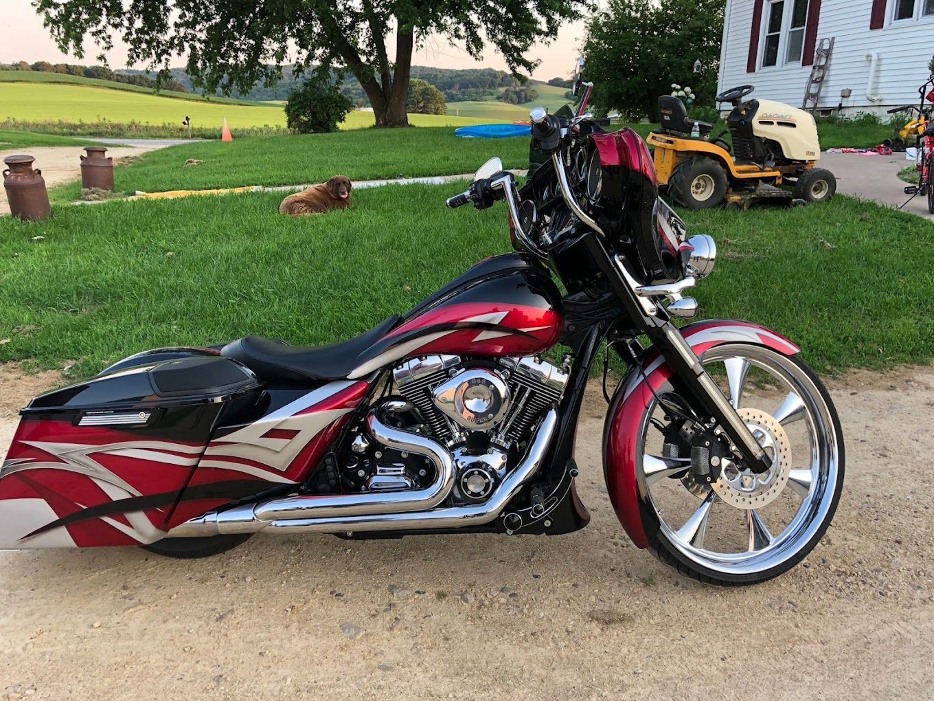 A red and black motorcycle is parked in a grassy field.