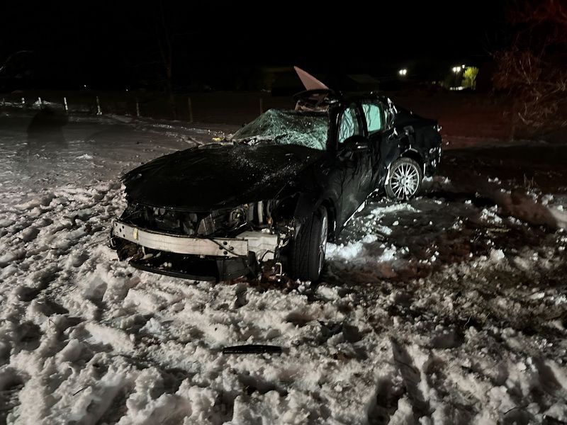 A car that has crashed into the snow at night.