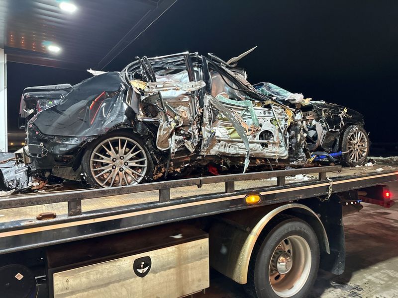 A wrecked car is being towed by a tow truck.
