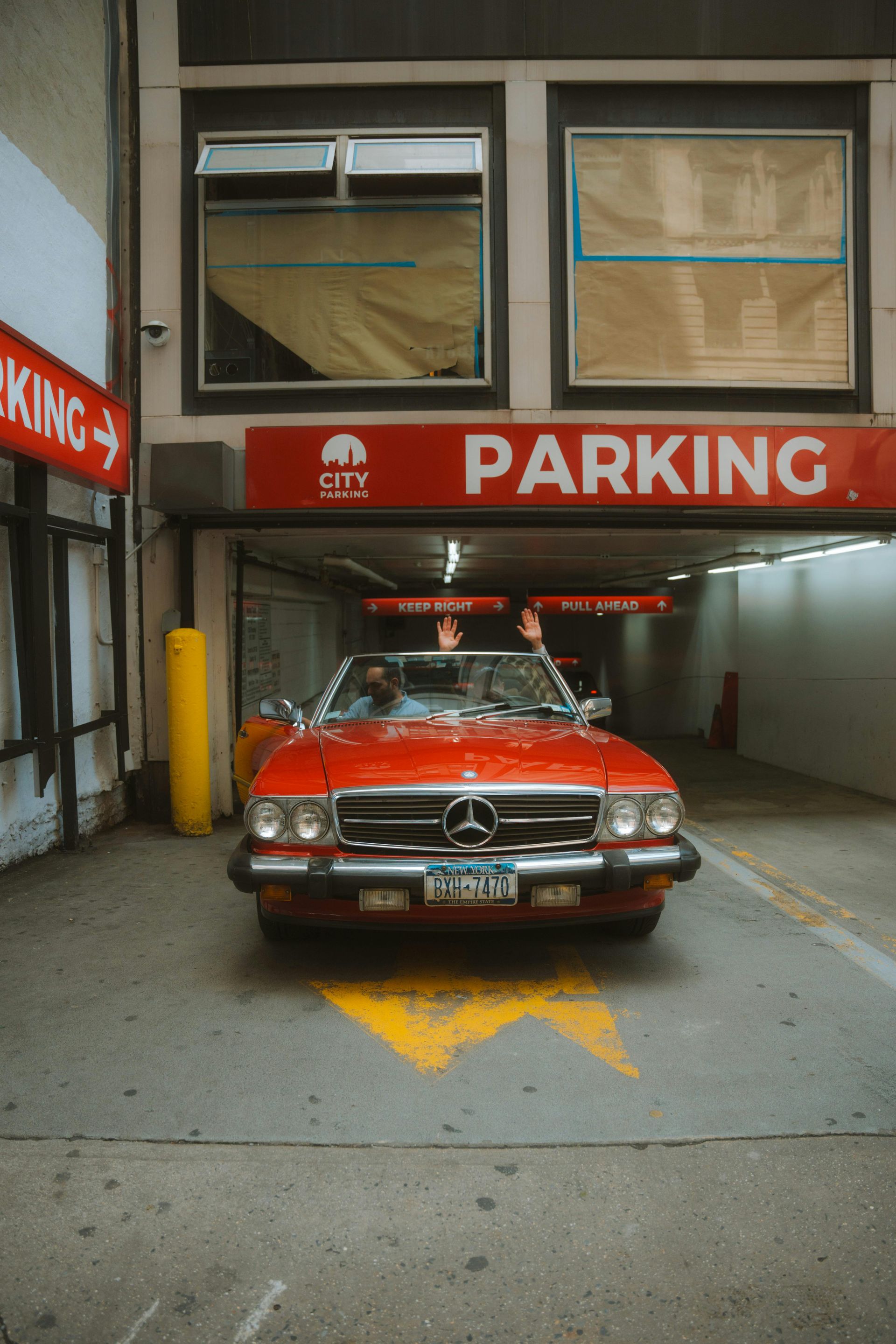 A red mercedes benz is parked in a parking garage.