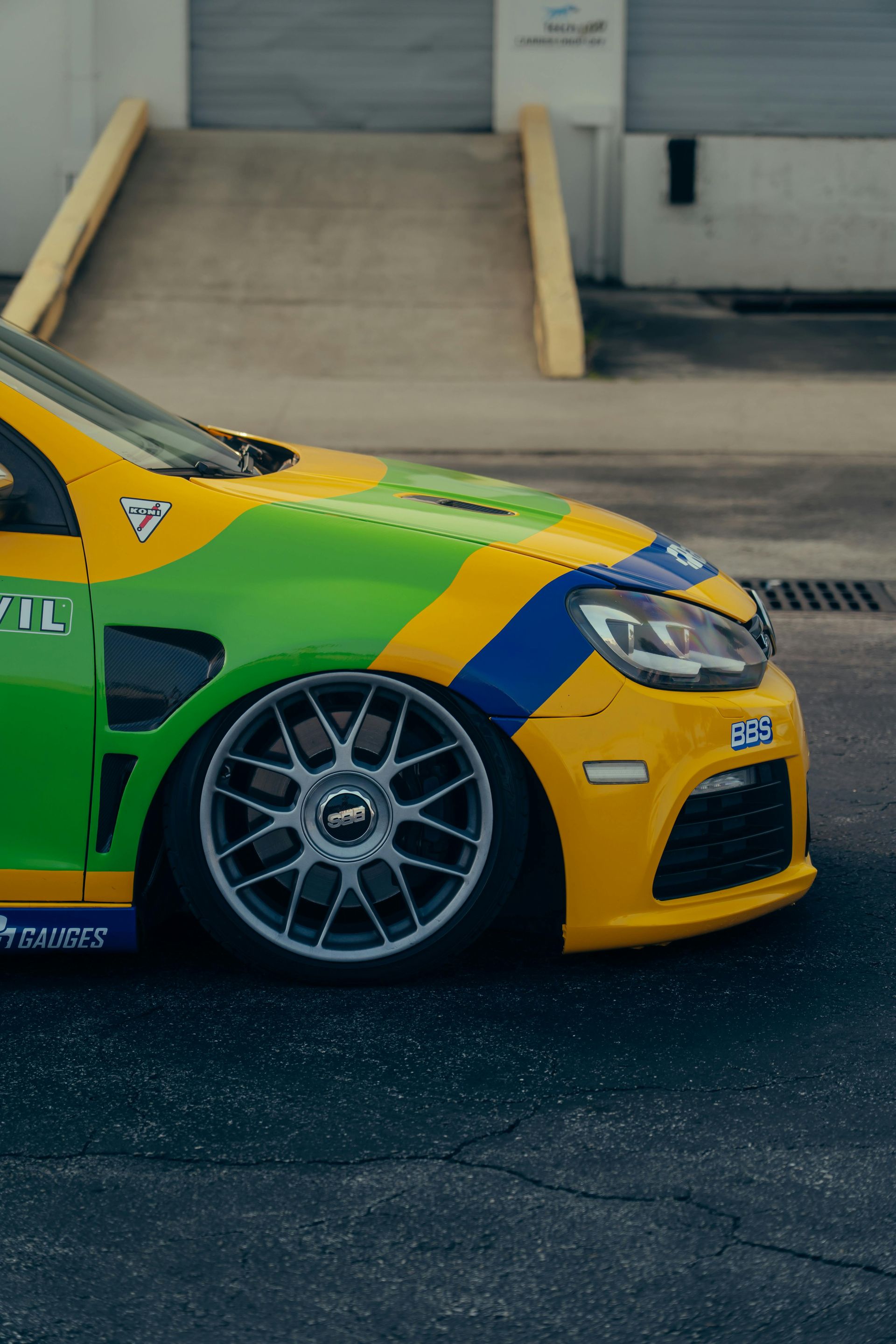 A yellow and green race car is parked in front of a building.