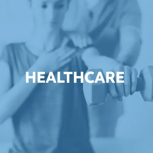 Woman working out with dumbbell; healthcare worker assisting.