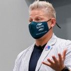 Man in blazer, wearing a mask that says 