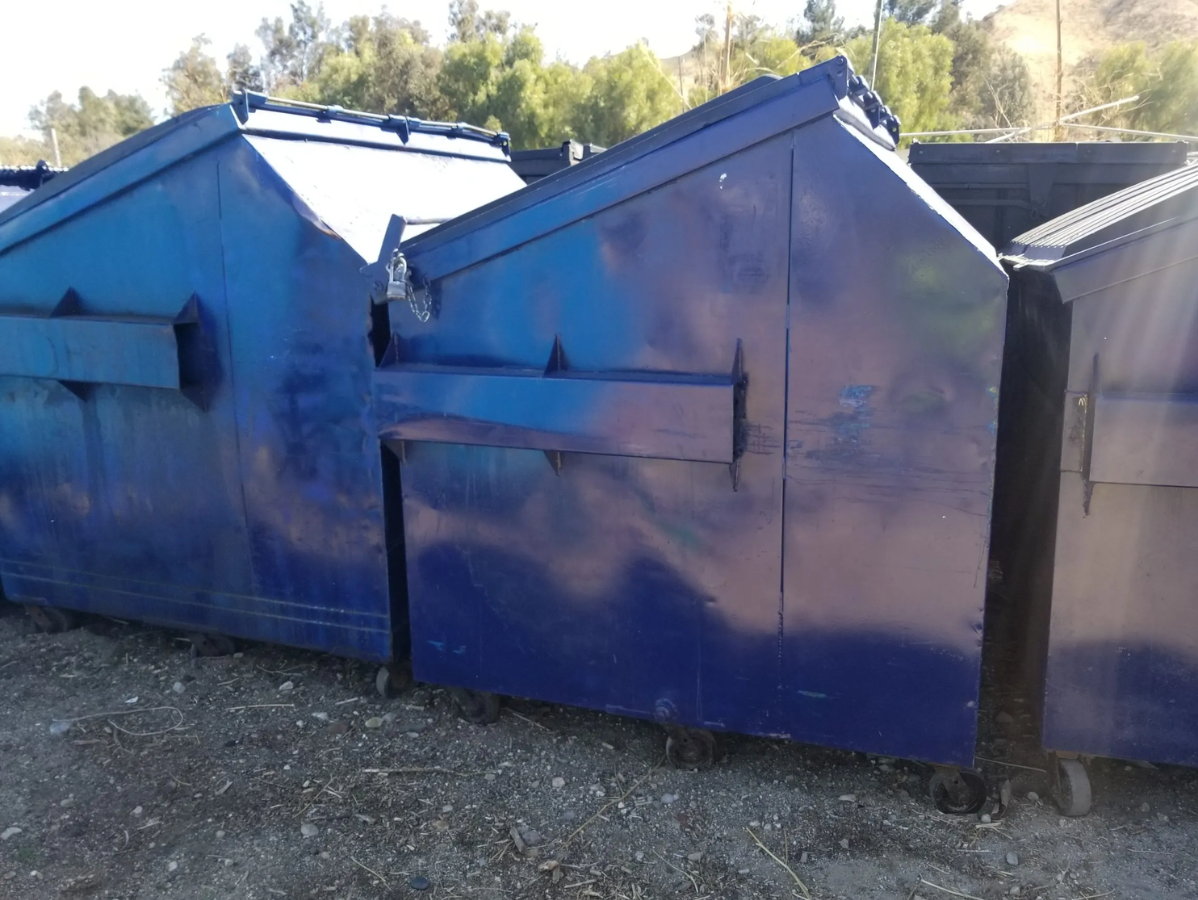 Blue metal dumpsters in an outdoor setting.