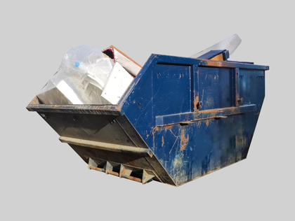 Blue dumpster in a driveway next to a brick building and a house with landscaping.
