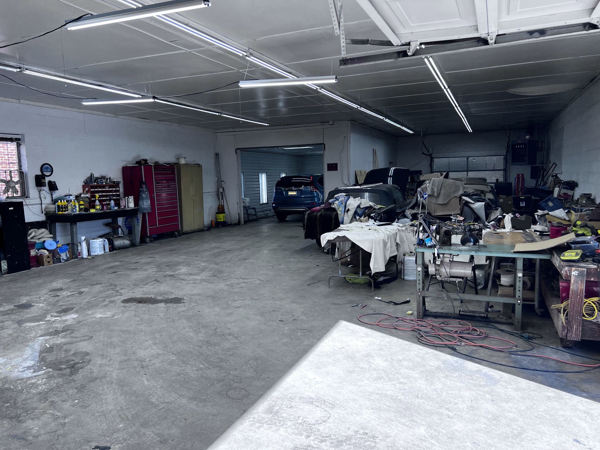 A garage filled with lots of tools and cars being worked on.