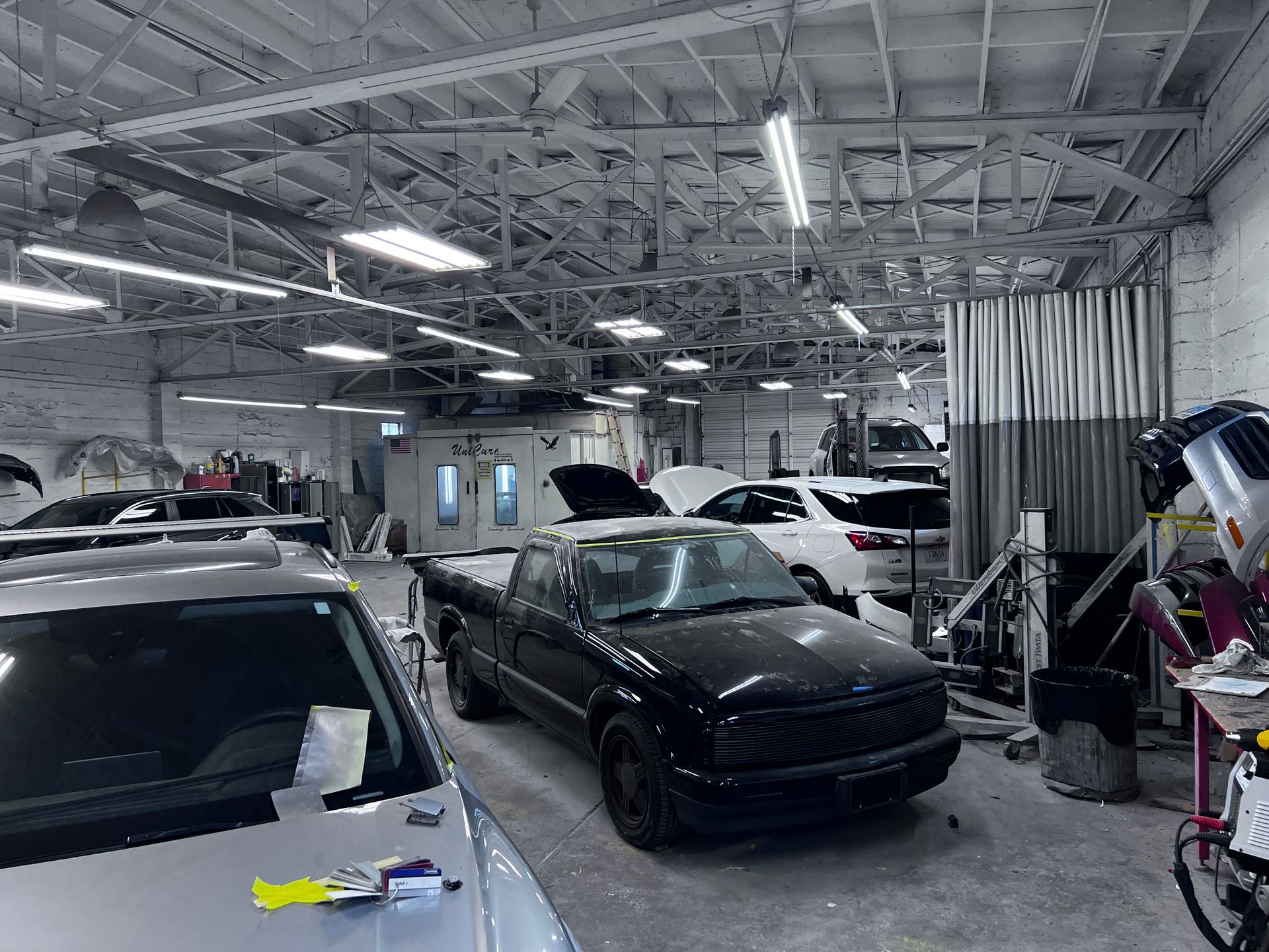 A black truck is parked in a garage with other cars.
