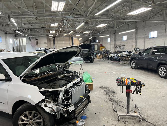 A car is being repaired in a garage with the hood up.