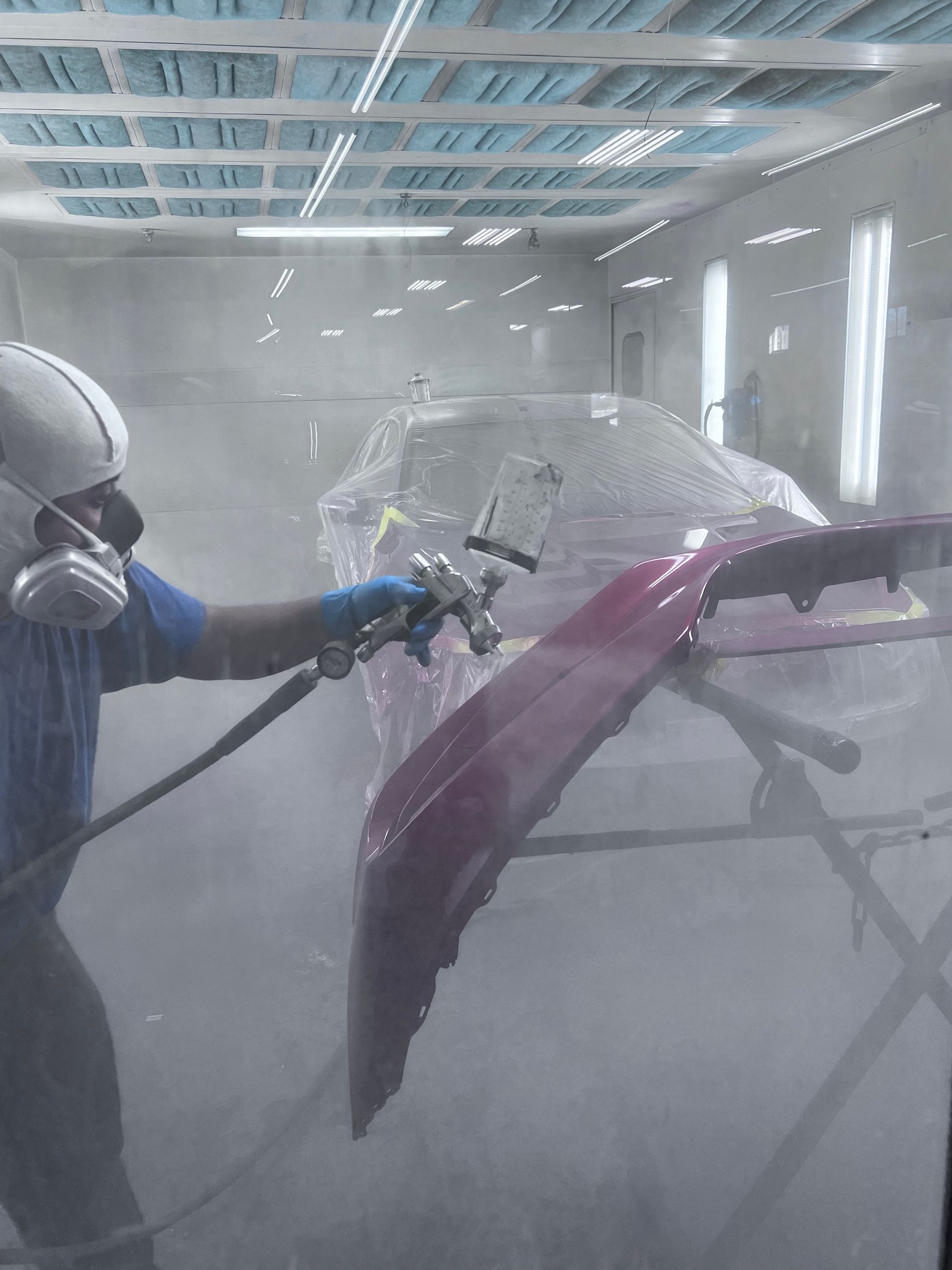 A man is spray painting a car in a paint booth.
