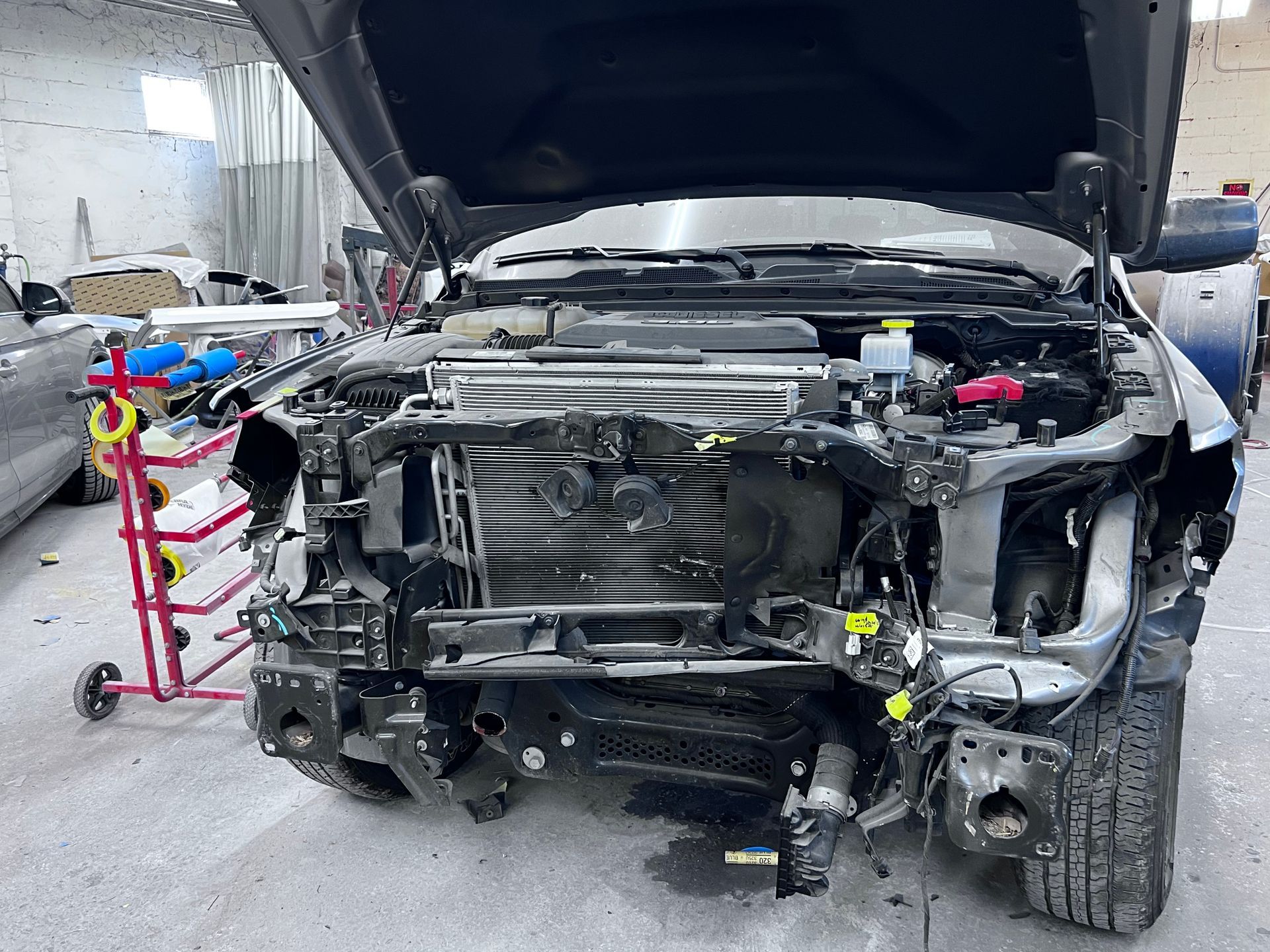 A truck is being repaired in a garage with the hood open.