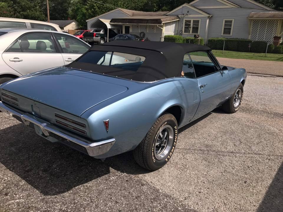 A blue car with a black top is parked in a parking lot.