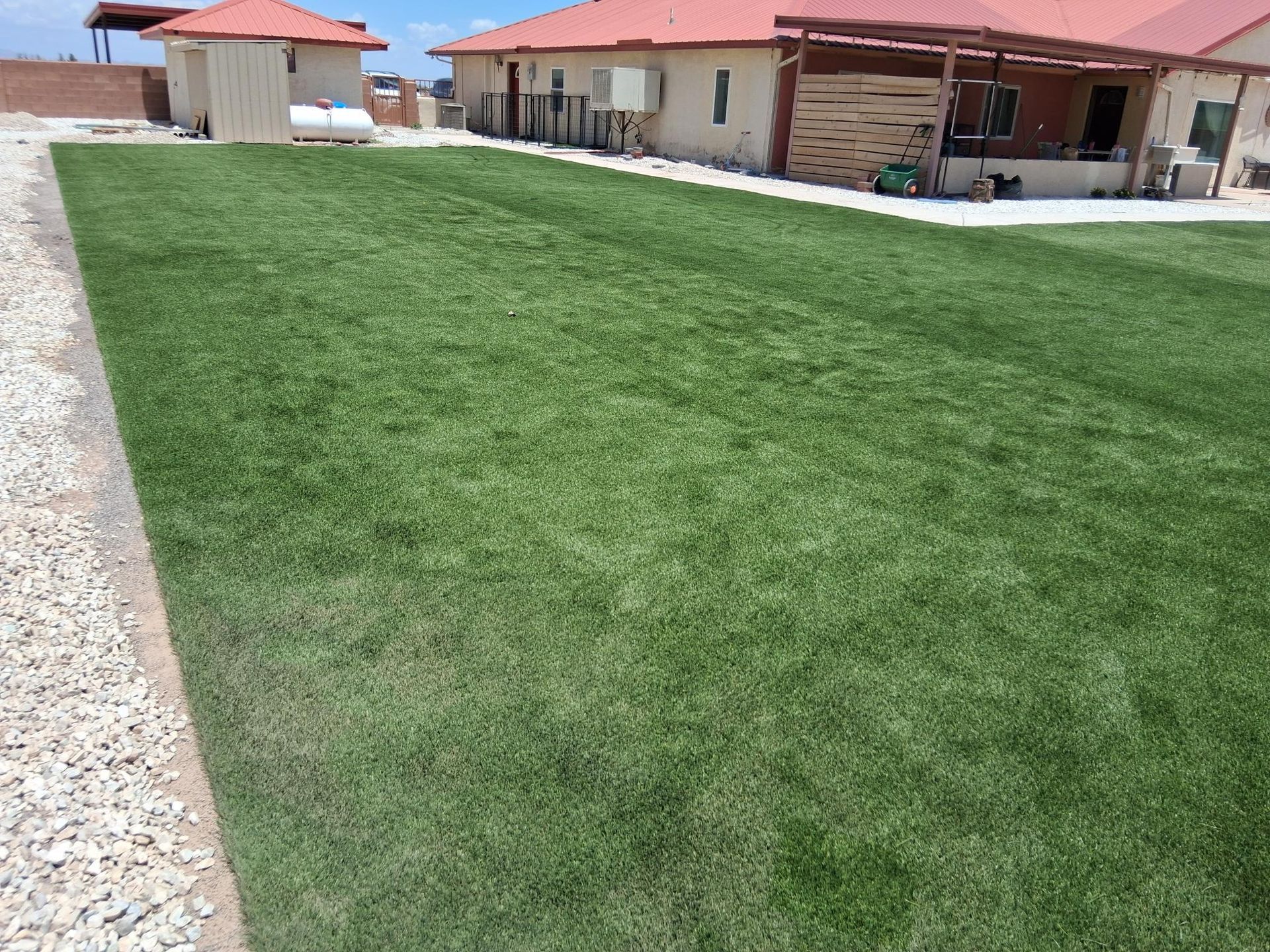 A large lawn in front of a house with a red roof.