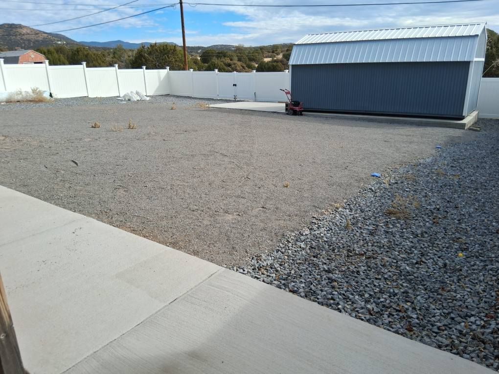 A gravel yard with a shed in the background
