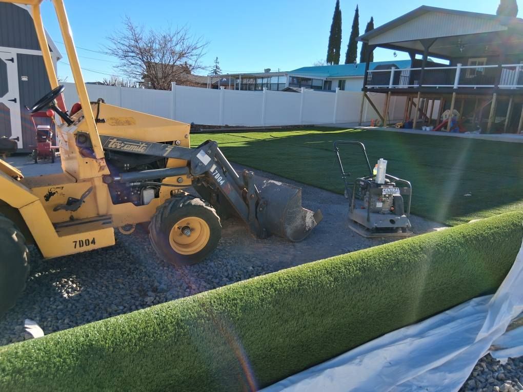 A yellow tractor is parked next to a pile of grass.