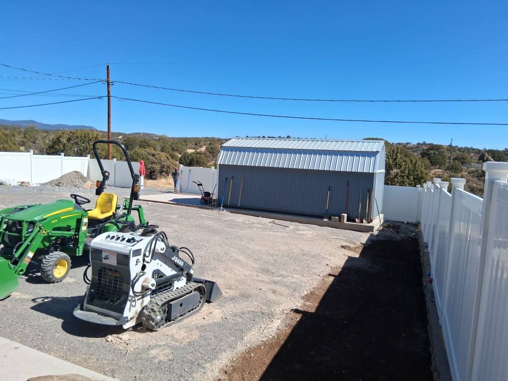 A green john deere tractor is parked in front of a white fence.