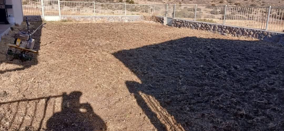 A shadow of a person is cast on a pile of dirt.