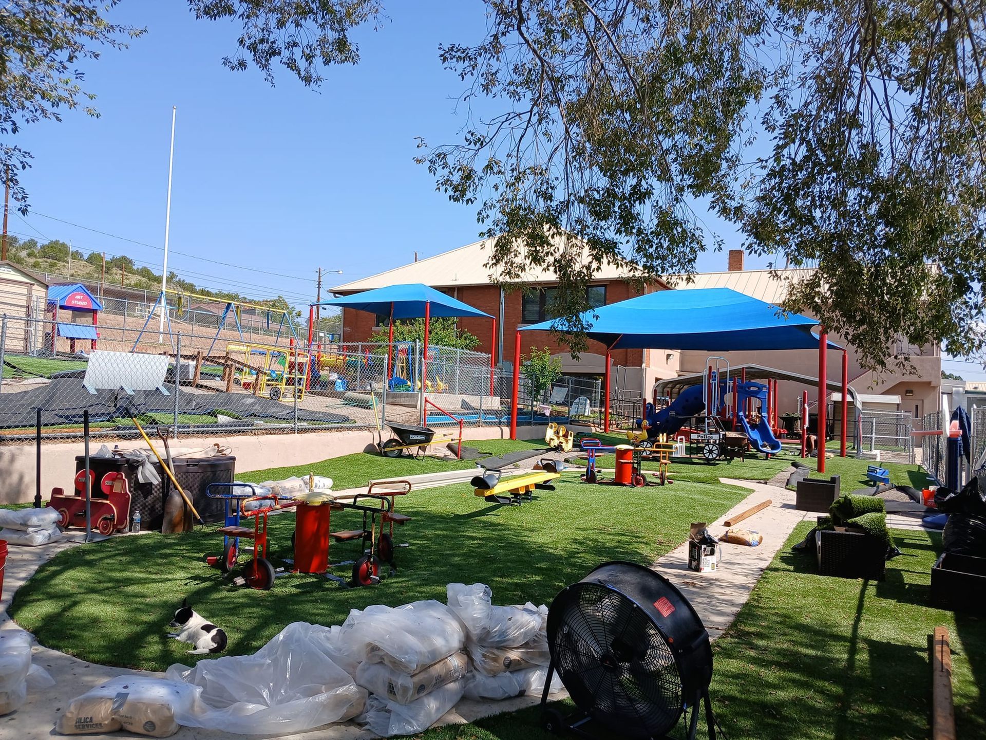 A playground is being built in a park with a blue umbrella