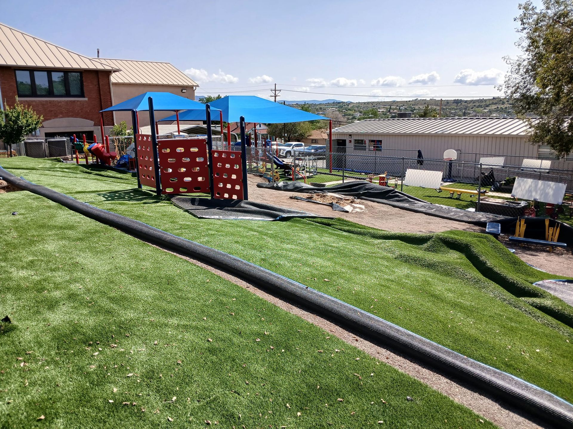 A playground is being built on a hill in front of a house.