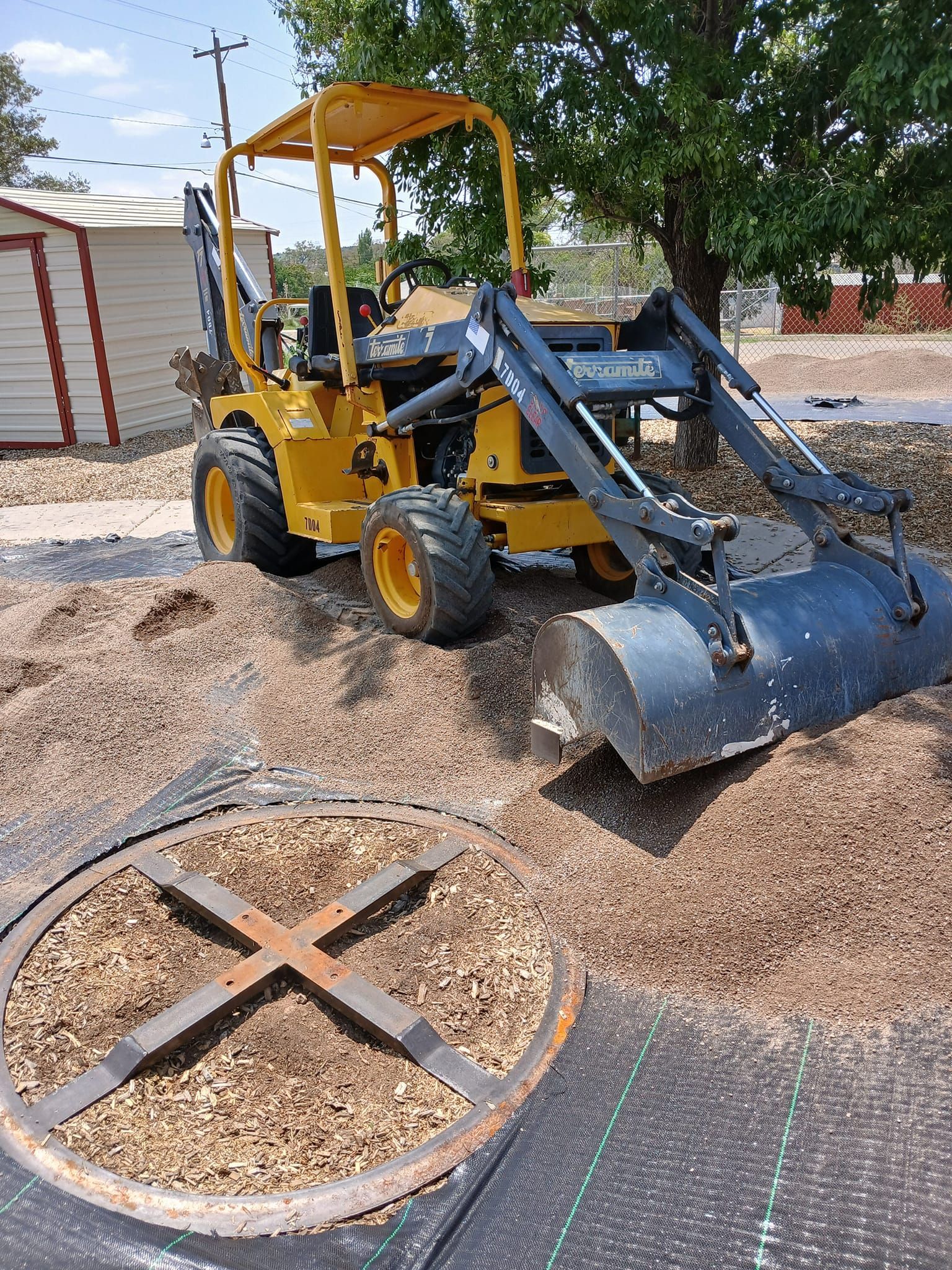 A yellow tractor is sitting on top of a pile of wood chips.