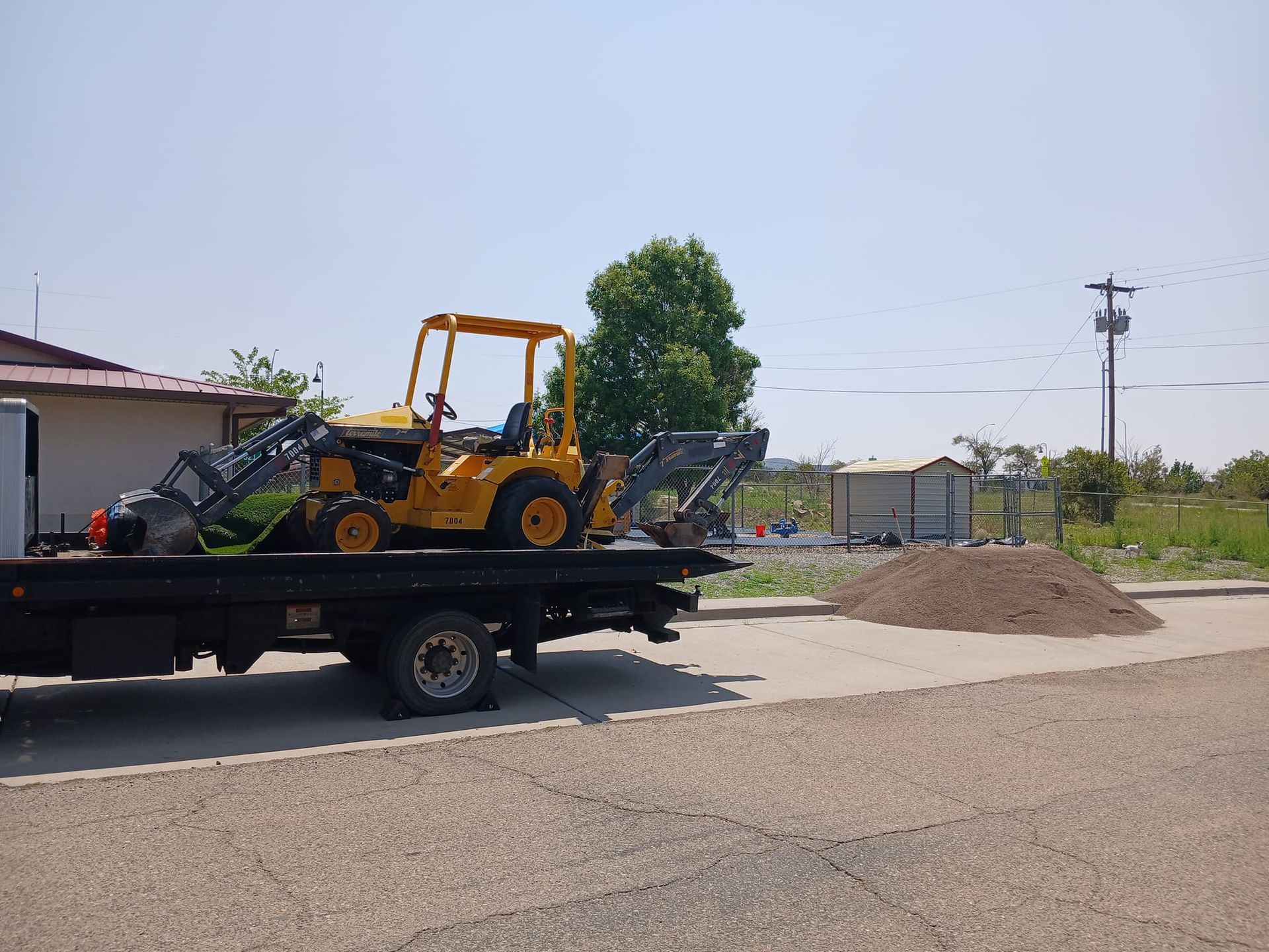 A yellow tractor is on the back of a tow truck