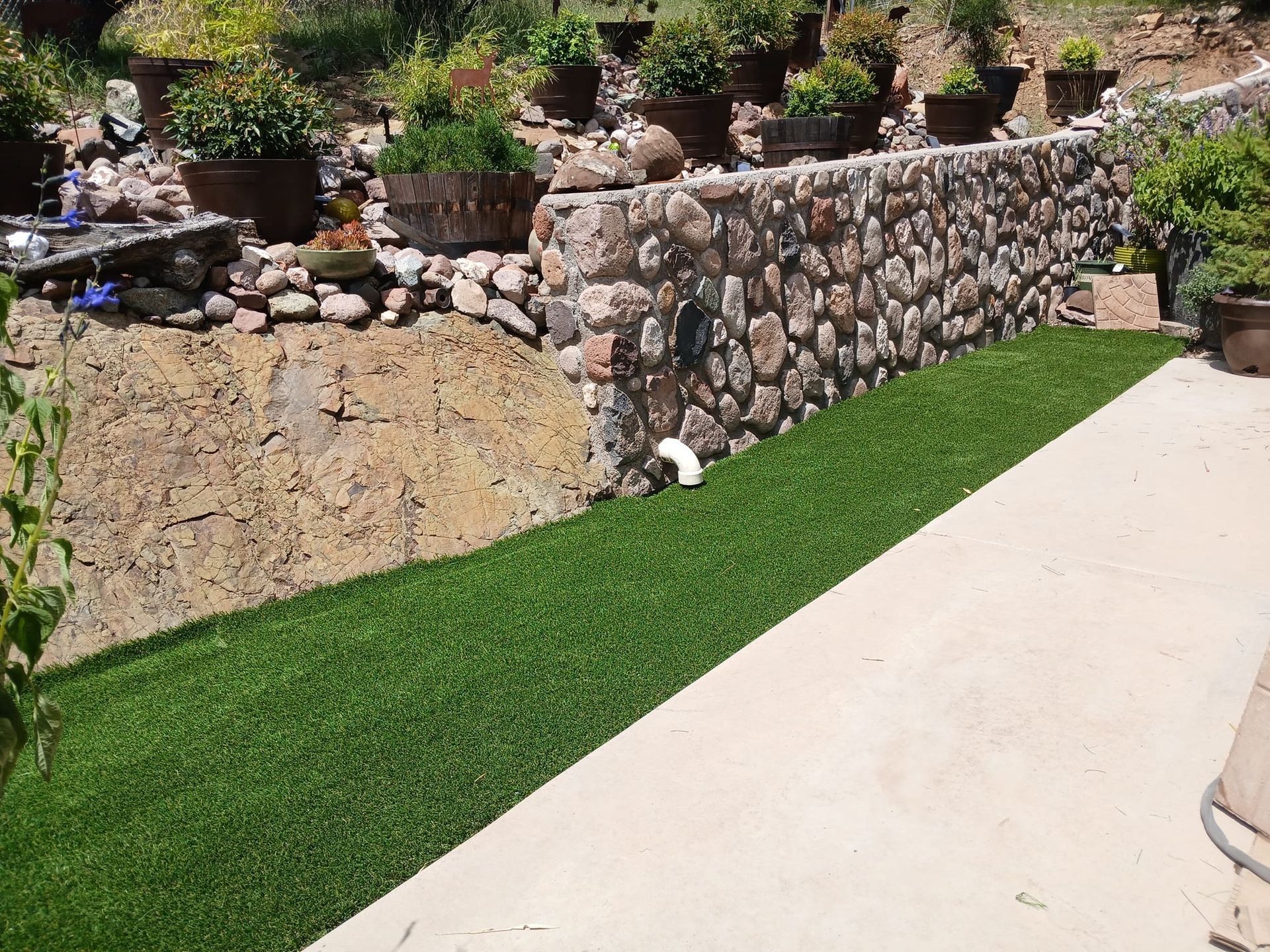 A stone wall surrounds a lush green lawn.