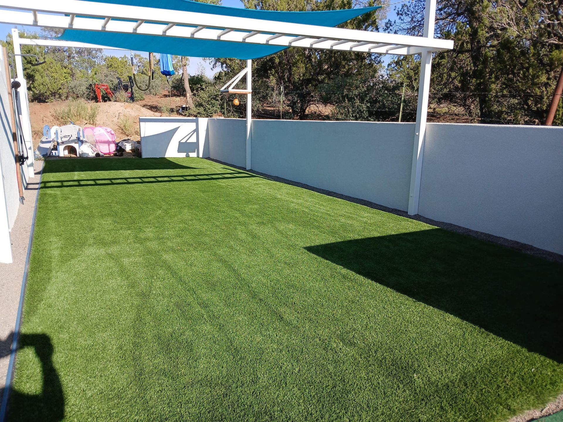 A large lawn with a white fence and a blue canopy.