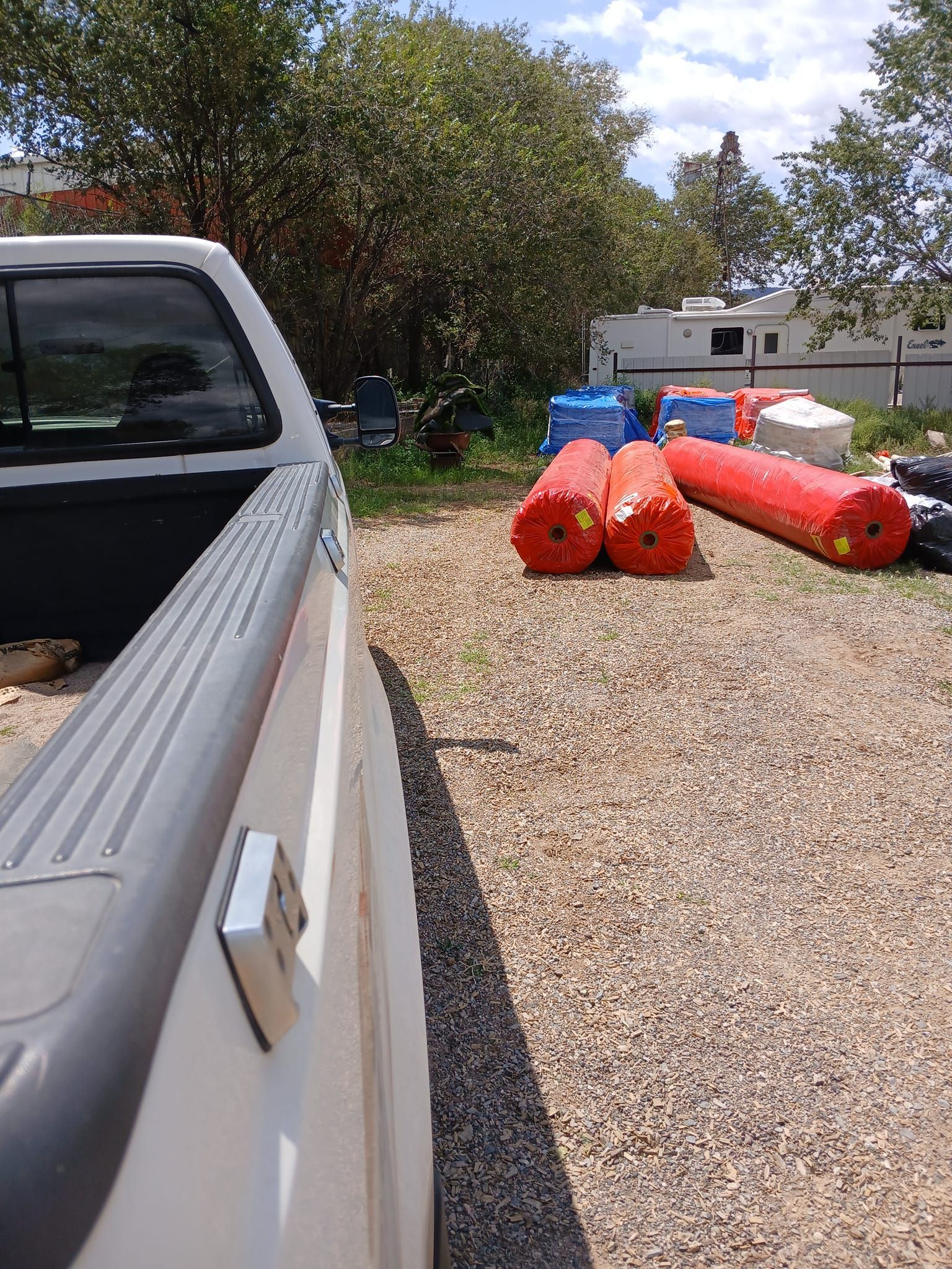 A white truck is parked in a gravel lot next to a bunch of inflatable tubes.