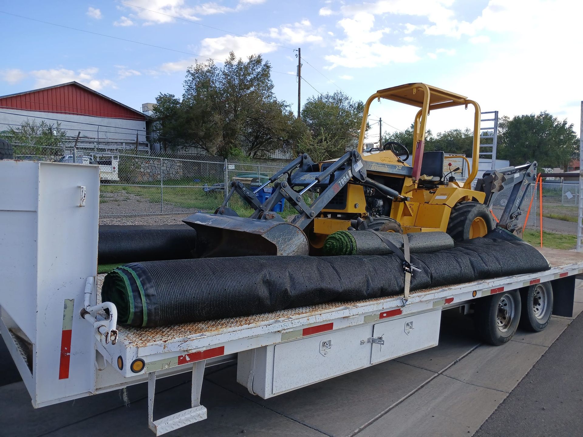 A yellow forklift is on the back of a flatbed trailer