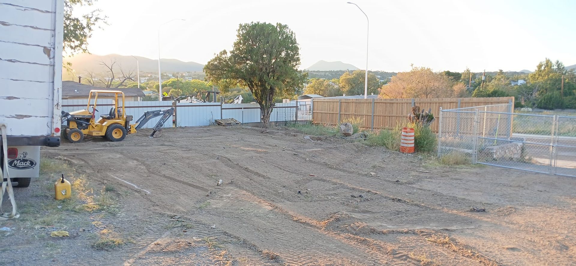 A tractor is parked in the dirt in front of a building.