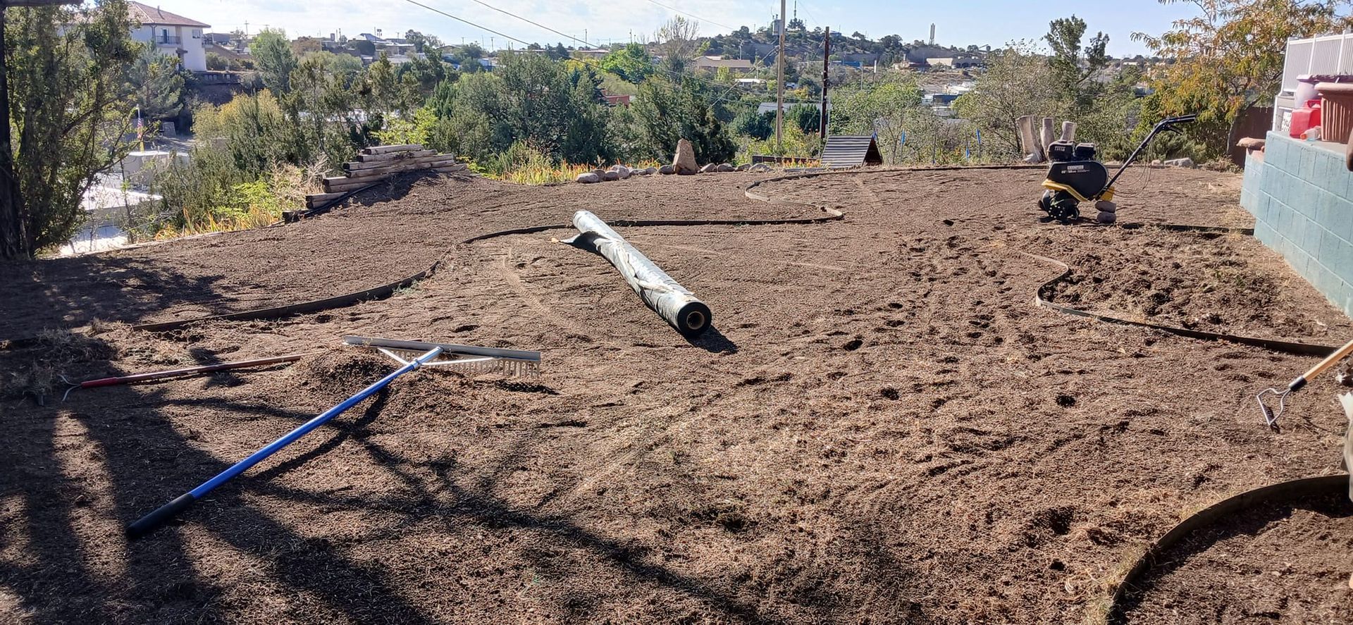 A person is raking a pile of dirt with a rake.
