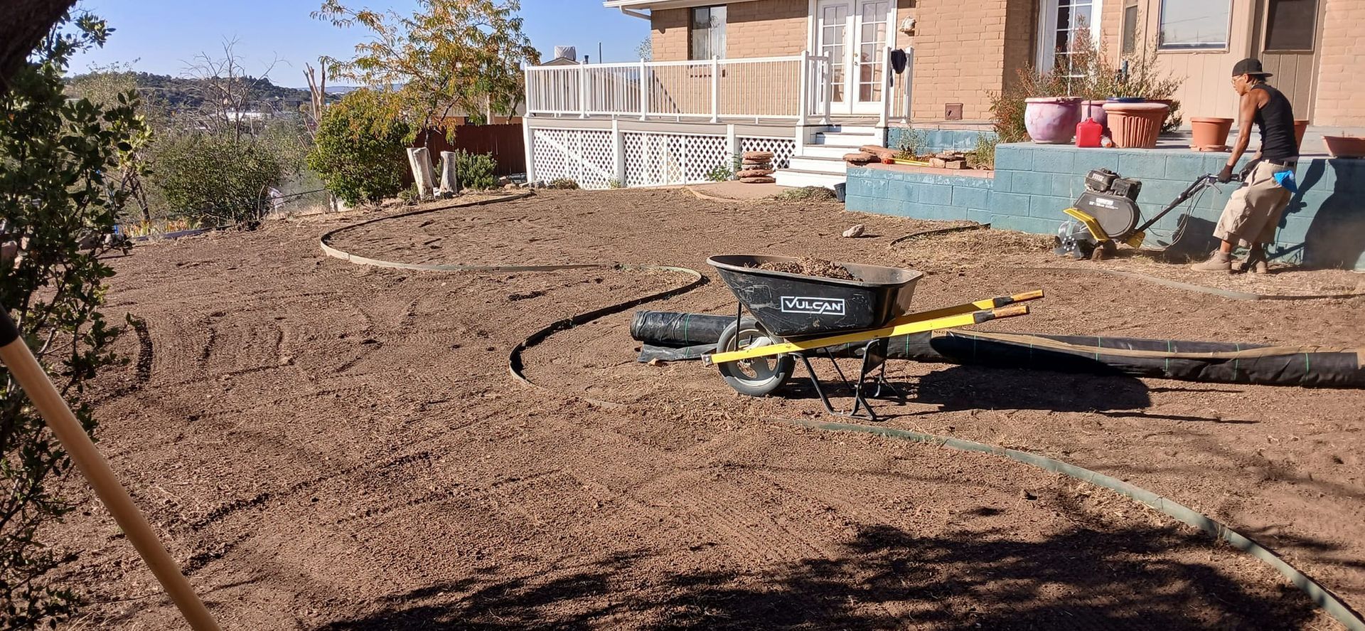 A wheelbarrow is sitting in the dirt in front of a house.