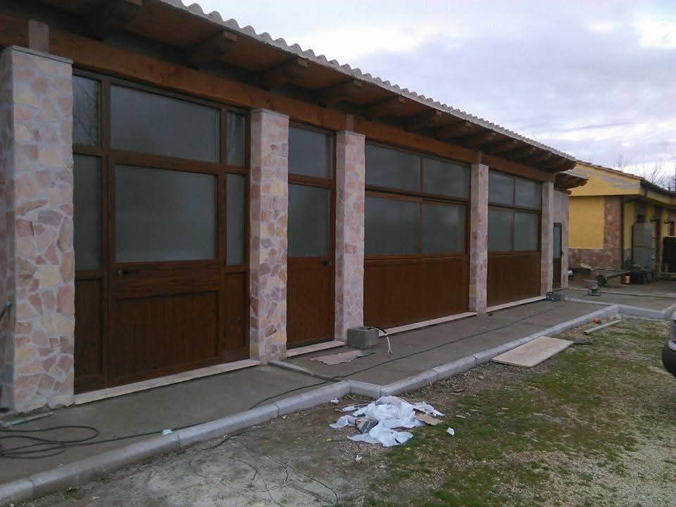 Esterno di un edificio marrone con pilastri in pietra e grandi finestre, con un marciapiede in cemento di fronte.