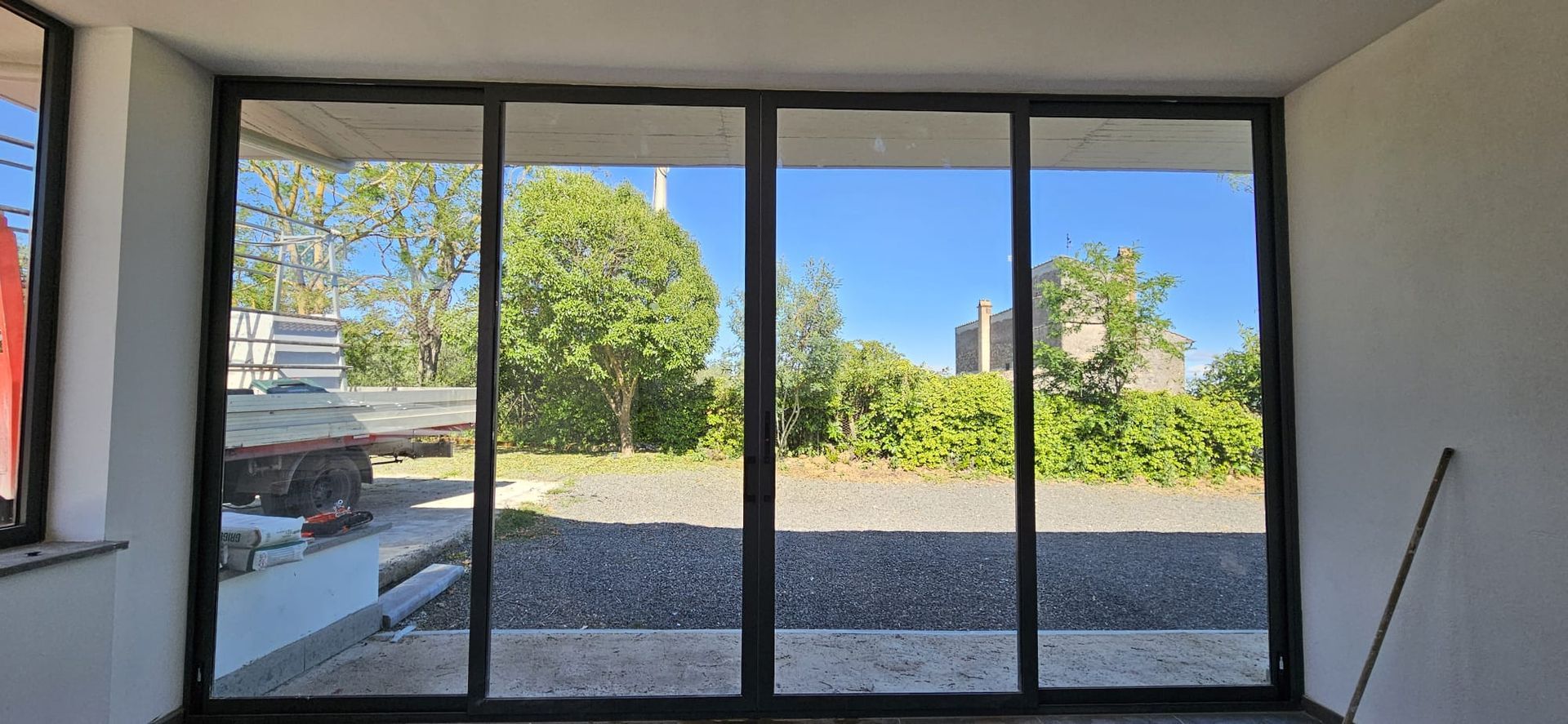 Porte in vetro che si affacciano sugli alberi e su un edificio contro il cielo azzurro.