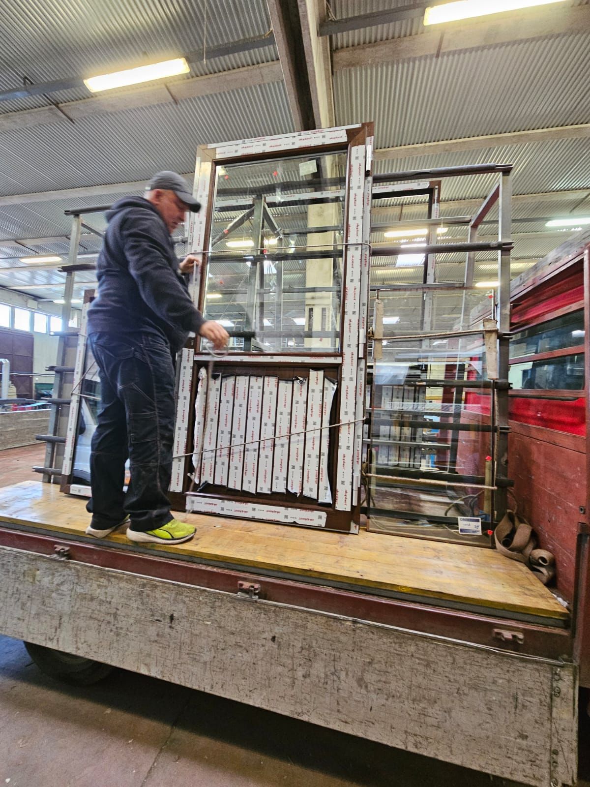 Uomo che sistema le finestre sul cassone di un camion in un magazzino.