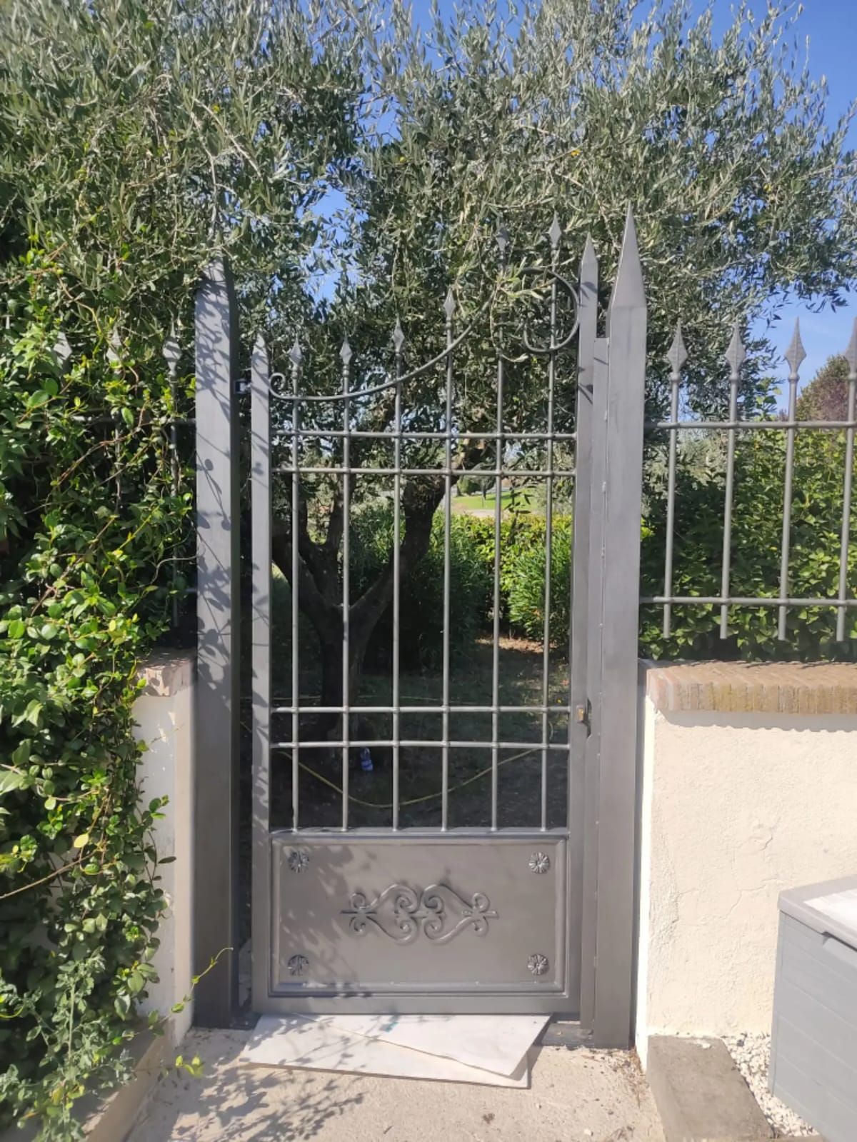 cancello in ferro battuto per passaggio pedonale in un terreno con degli ulivi