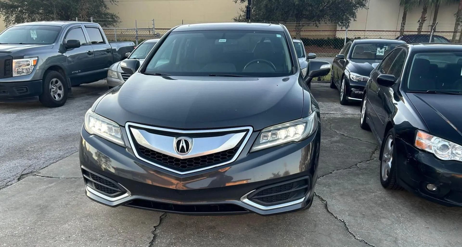 Dark gray Acura RDX SUV parked outside on a sunny day.