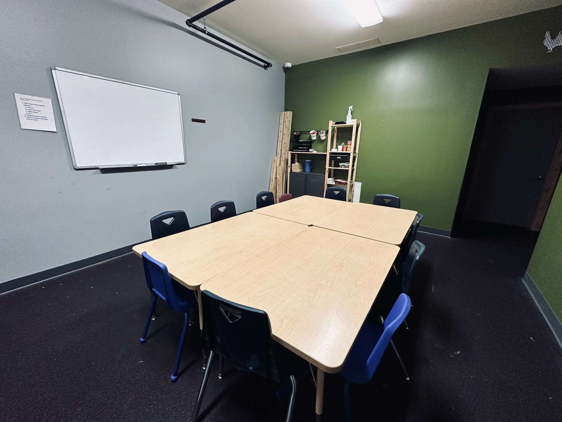 A conference room with tables and chairs and a whiteboard