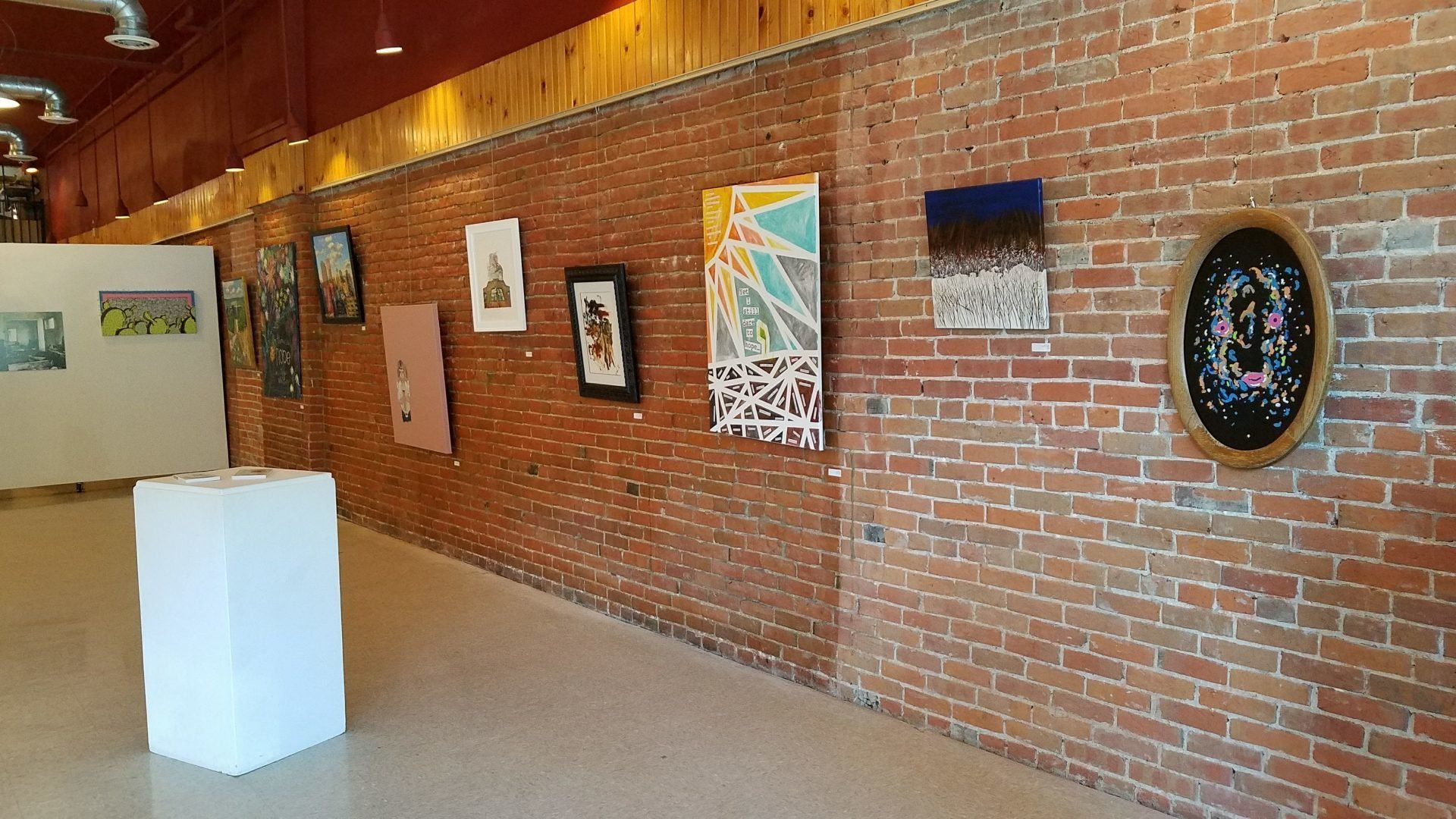 A room with a brick wall and paintings on it.