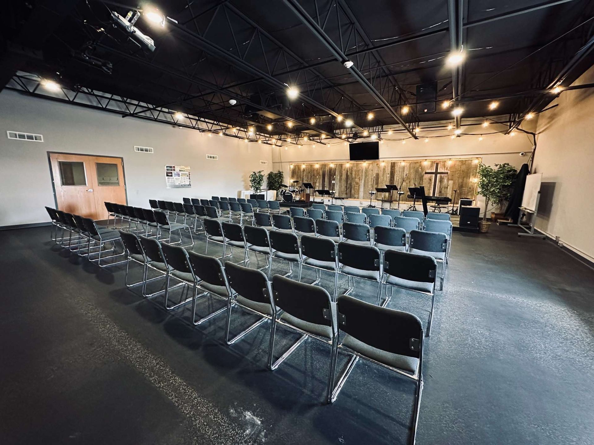 A large room with rows of chairs and a cross on the wall.