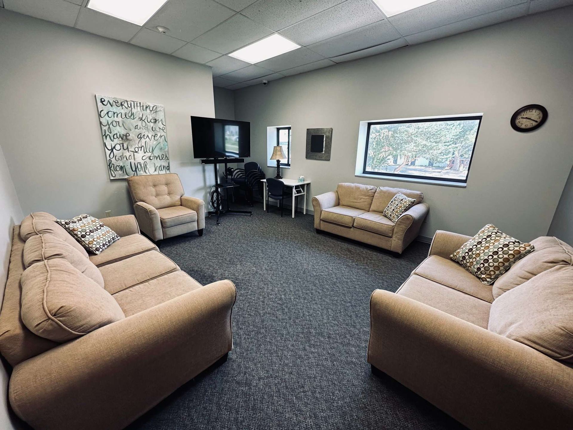 A living room filled with furniture and a clock on the wall.