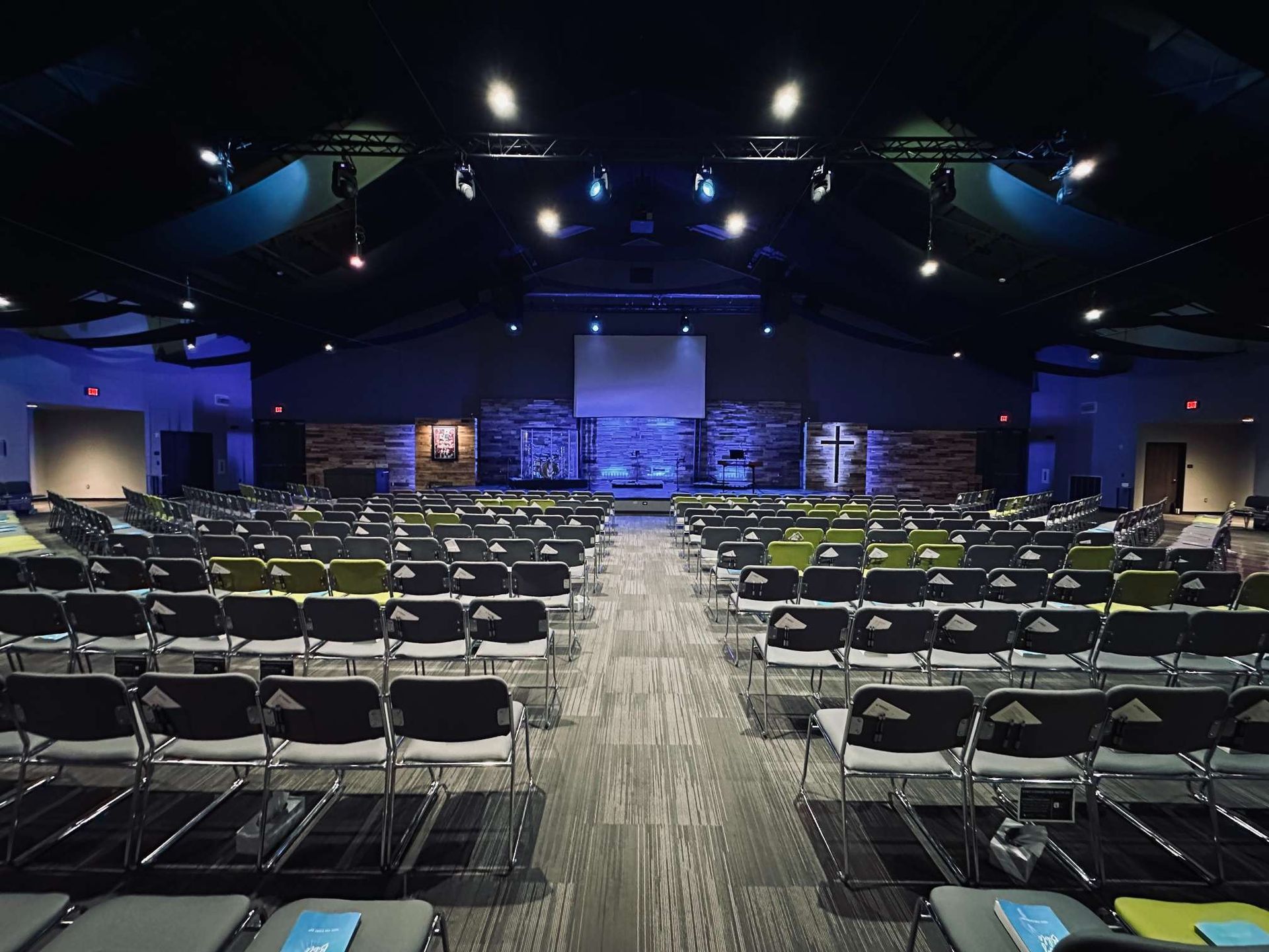 A large auditorium with rows of chairs and a projector screen