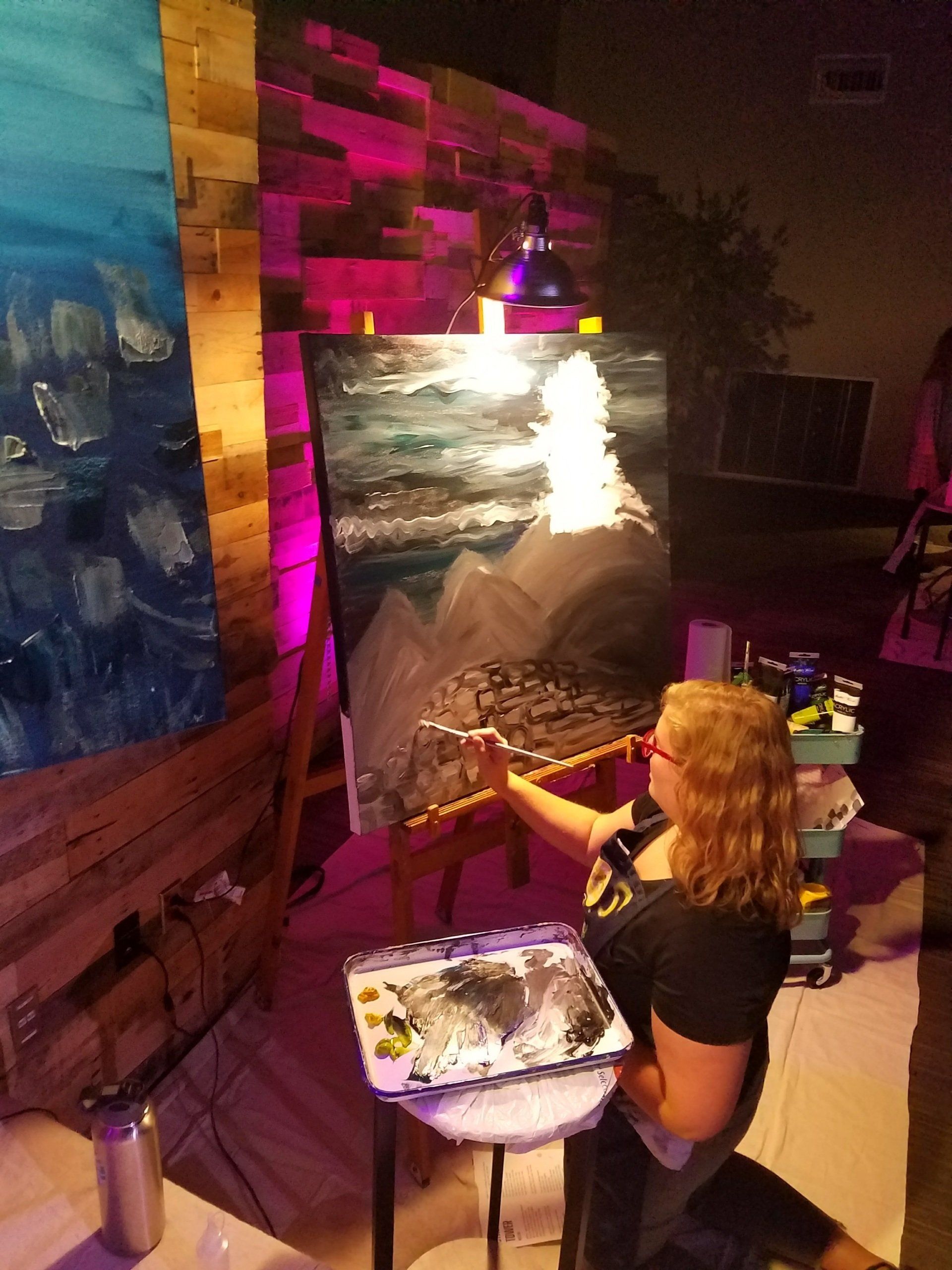 A woman is painting a picture on an easel
