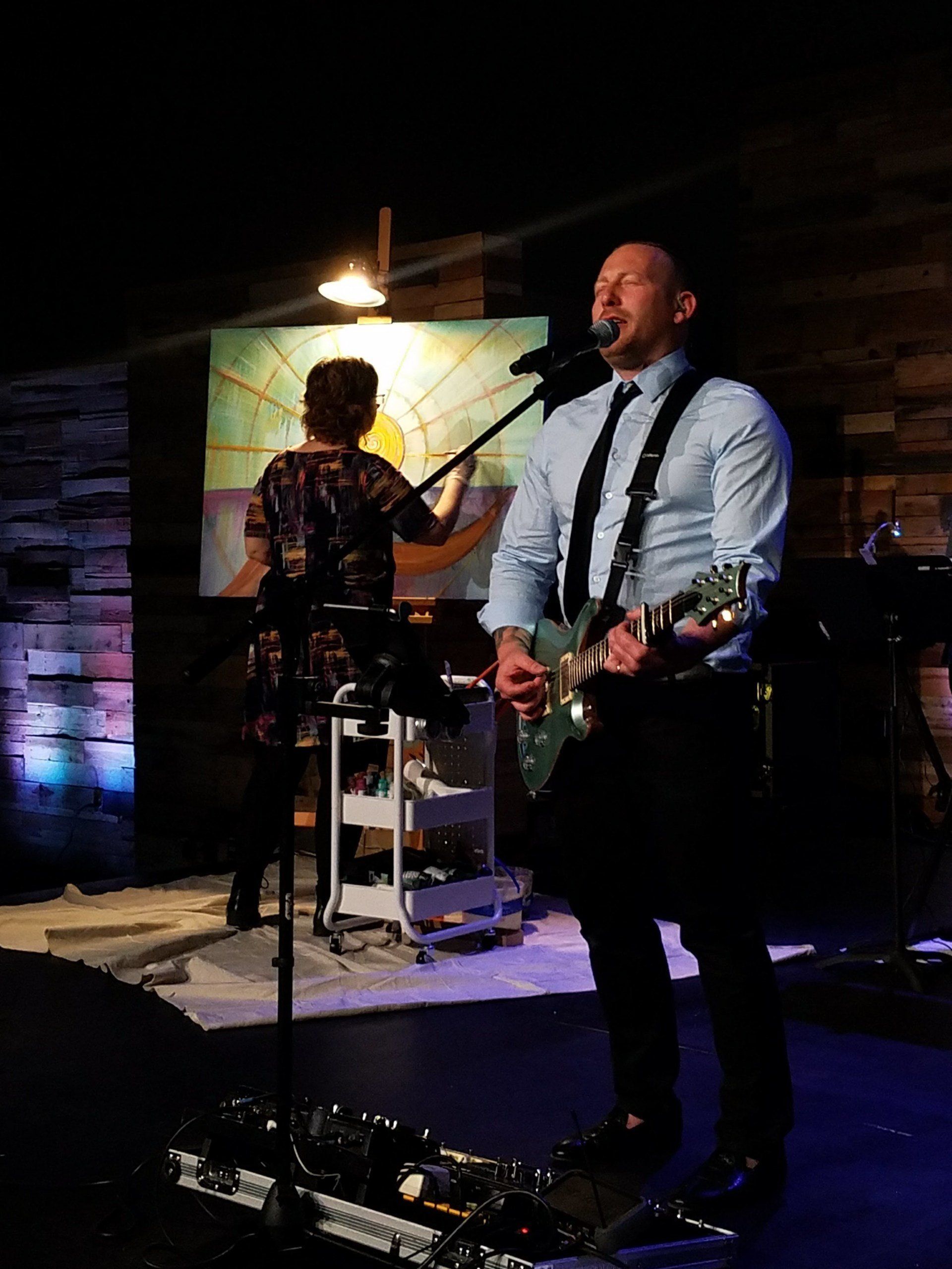 A man is singing into a microphone while playing a guitar.