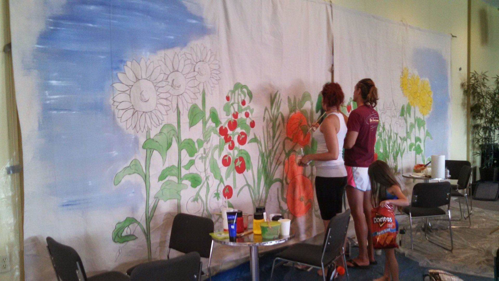 A group of people are painting a mural on a wall.