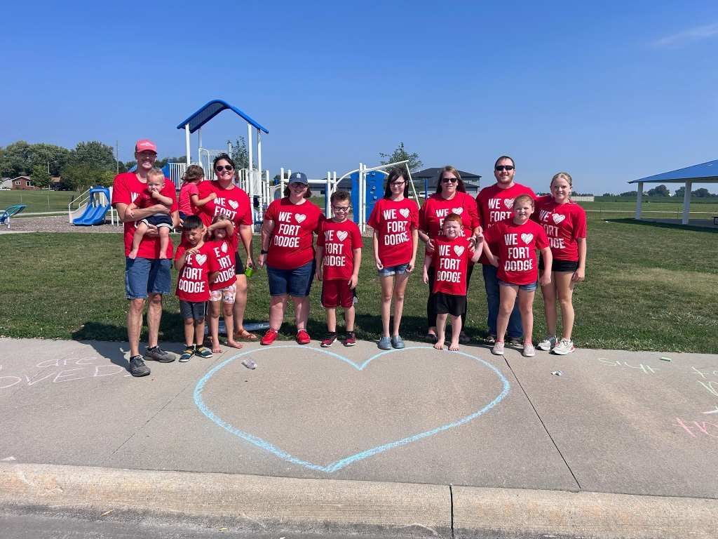 A group of people are standing on a sidewalk in front of a playground.