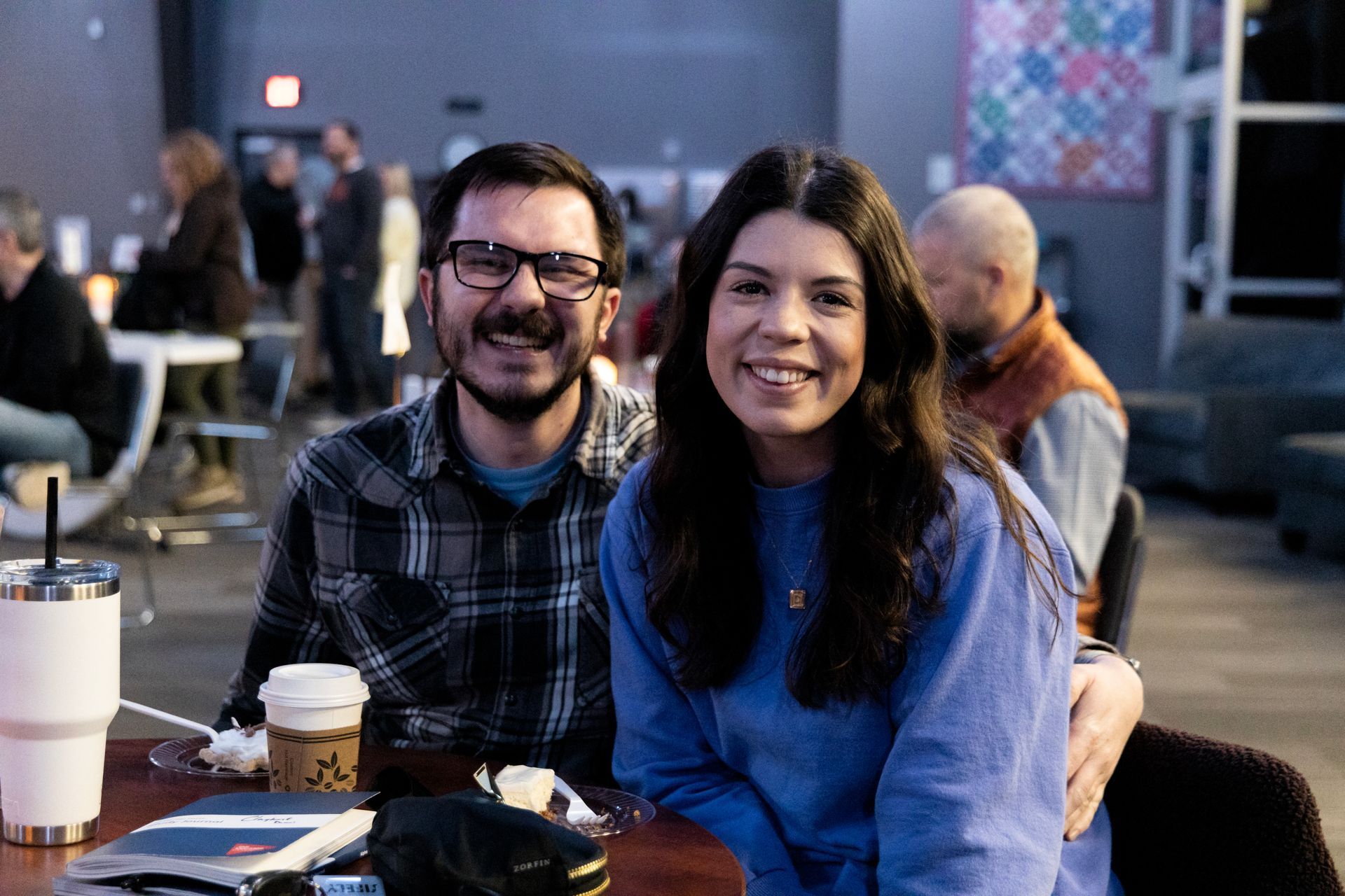 A man and a woman are posing for a picture while sitting at a table.