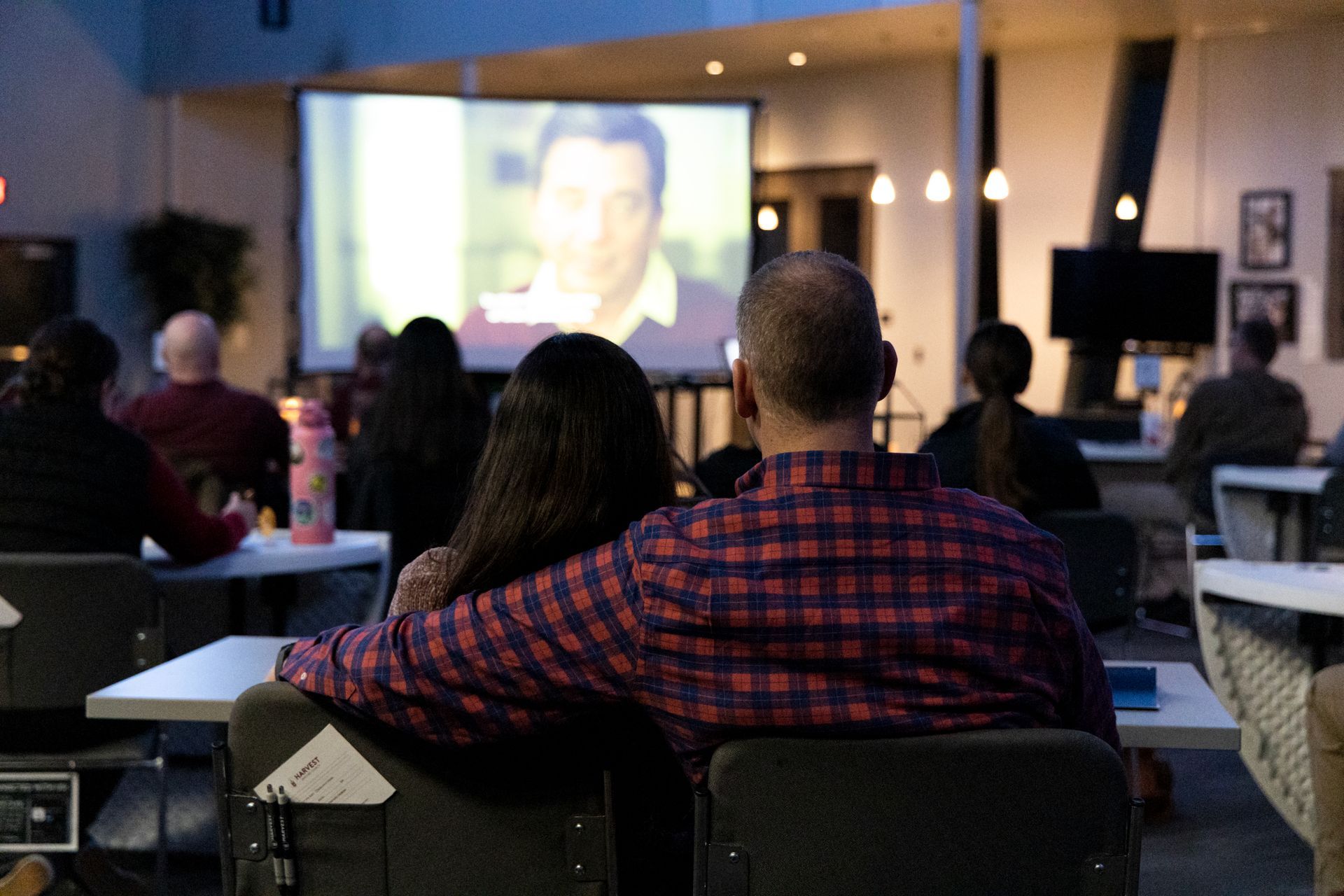 A man and a woman are sitting in front of a large screen watching a movie.