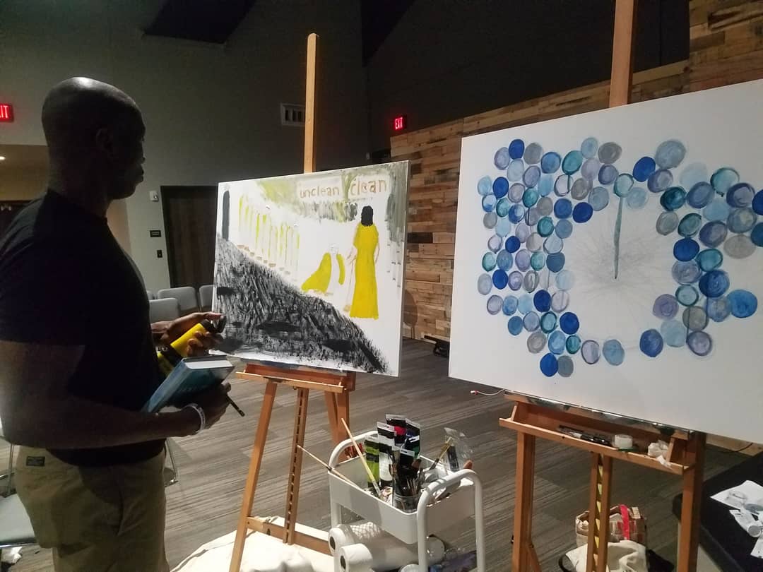 A man is painting a picture on an easel.