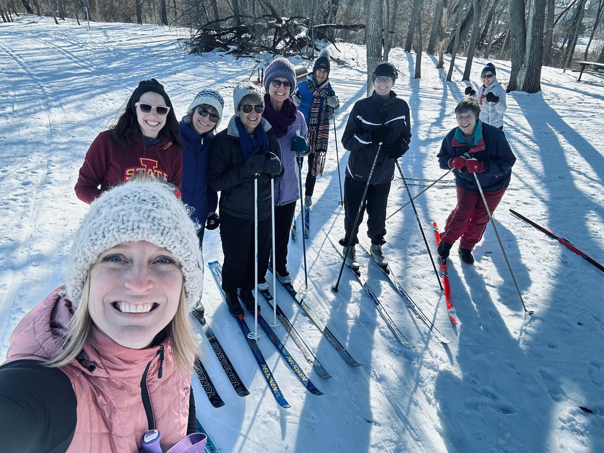 A group of people are taking a selfie while cross country skiing in the snow.