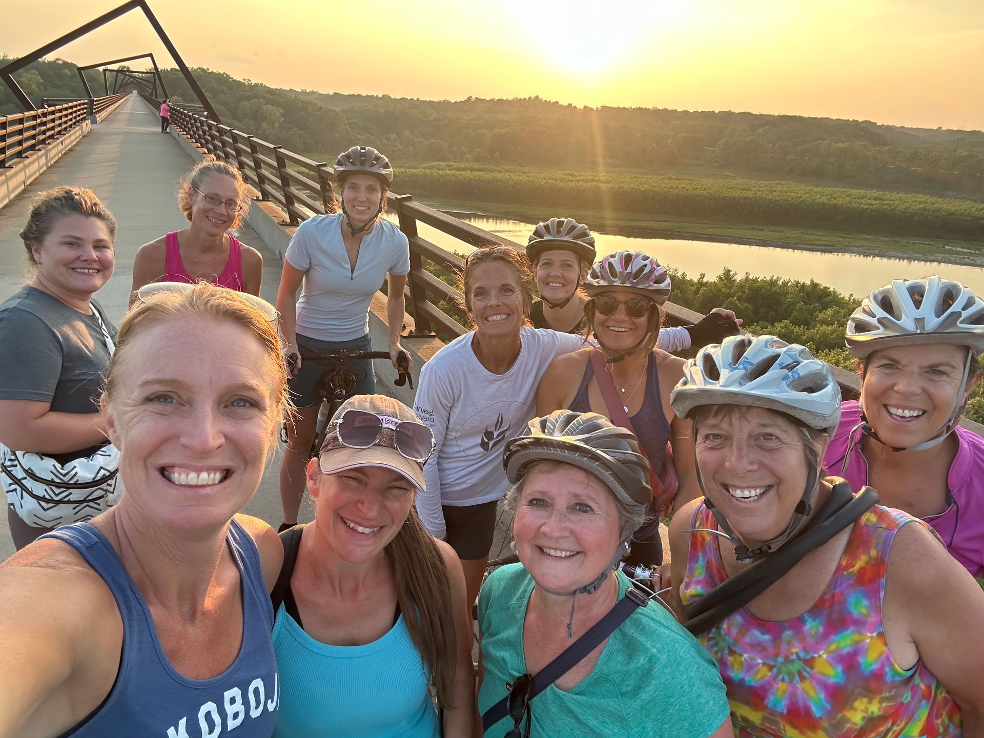 A group of women wearing helmets are posing for a picture on a bridge.